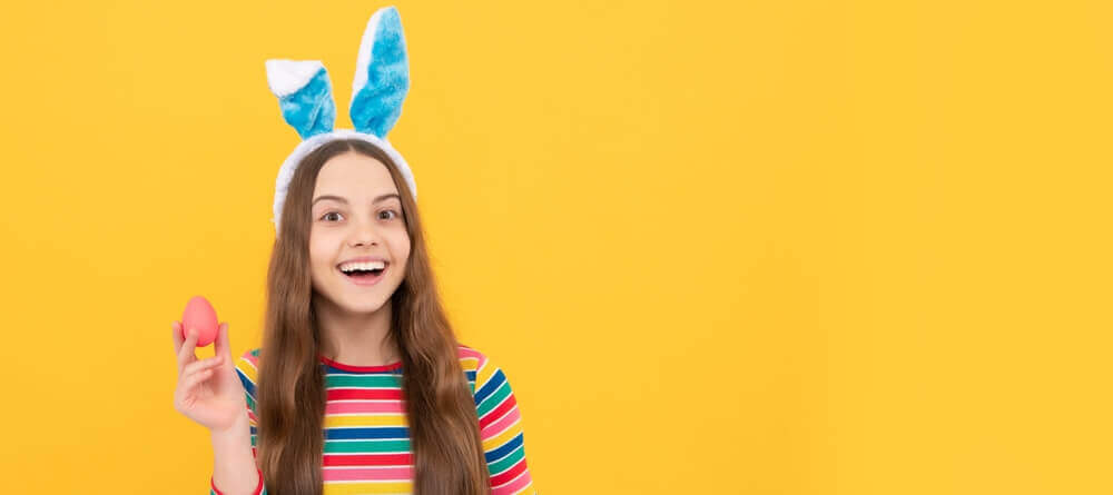 Older kid smiles and holds plastic Easter egg